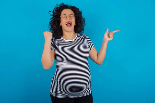 Cheerful Pregnant Arab Woman Wearing Striped Shirt Showing Copy Space — Stock Photo, Image