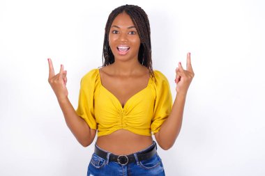 Sarı bluz ve kot pantolon giyen genç ve güzel bir kadın rock 'n roll tabelasını kendinden emin ve neşeli gösteriyor. 