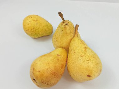 Minimalist stüdyo görüntüsü. Temiz beyaz arka planda birkaç tane taze sarı armut var. Kompozisyon, doğal dokuyu, organik şekilleri ve meyvelerin sıcak tonlarını vurgular. Sağlıklı beslenme kavramları ve gıda pazarlaması için uygundur., 