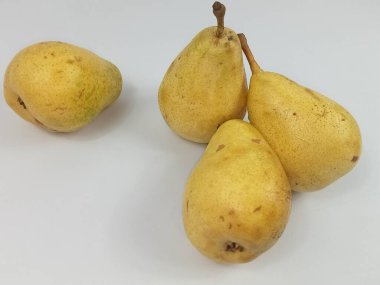 Temiz beyaz arka plana yerleştirilmiş bir grup taze sarı armut. Basit stüdyo kompozisyonu meyvenin doğal dokusunu, rengini ve organik kusurlarını vurgular. Gıda, beslenme, sağlıklı beslenme ve taze yemek temaları için uygundur. 
