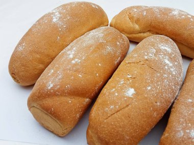 Temiz bir zemin üzerine un serpiştirilmiş taze altın sarısı fırın ekmek rulolarını kapatın. Ev yapımı, yumuşak dokuma ve sıcak pişirme atmosferi. Fırın menüleri, yemek paketleri, tarif blogları, yemek temaları ve organik ekmek Conce için ideal