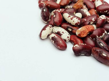 Kuru kırmızı ve benekli fasulyeler, fotokopi alanı olan beyaz bir arkaplanda. Sağlıklı beslenme, vejetaryen beslenme, yemek malzemeleri ve gıda tasarımı için organik baklagiller konsepti. Düz konum.