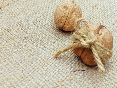 Taşralı çuval bezi kumaşına doğal sicimle bağlanmış cevizler. Fotokopi uzayı ile organik ve çevre dostu gıda konsepti. Doğal doku, sürdürülebilir yaşam tarzı, sıfır atık ambalaj, sağlıklı beslenme ve tarım ürünü teması. İdeal