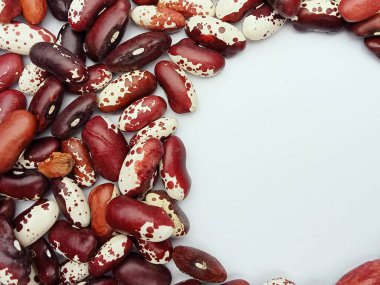 Kırmızı ve beyaz kuru fasulyeler temiz beyaz bir zemin üzerinde sınır çerçevesi olarak düzenlenir. Ortasında da kopya alanı bulunur. Doğal bitkisel gıda konsepti ve organik doku. Gıda ambalajı tasarımı, yemek tarifleri, market reklamları, vegan beslenme için ideal.