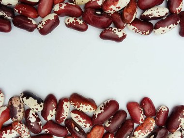 Kırmızı ve beyaz kuru fasulyeler temiz beyaz bir zemin üzerinde üst ve alt sınır çerçevesi olarak düzenlenir. Ortasında da fotokopi alanı bulunur. Doğal bitkisel gıda konsepti ve organik doku. Gıda ambalajı tasarımı, yemek tarifleri, market reklamları için ideal.