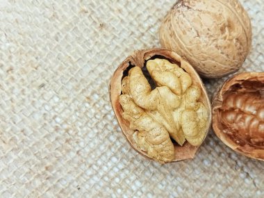 Doğal çuval bezi kumaşında kırılmış bir kabuğun içindeki ceviz çekirdeğinin yakın çekimi. Kırsal gıda geçmişi, sağlıklı organik fındık konsepti, makro doku..