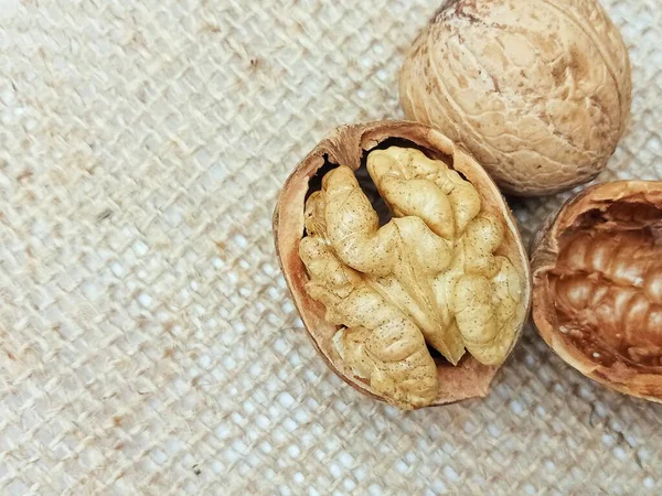 Doğal çuval bezi kumaşında kırılmış bir kabuğun içindeki ceviz çekirdeğinin yakın çekimi. Kırsal gıda geçmişi, sağlıklı organik fındık konsepti, makro doku..