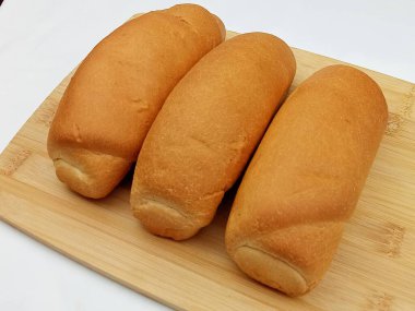 Tahtaya yerleştirilmiş ve beyaz arka planda izole edilmiş birkaç tane taze ekmek rulosu. Yemek reklamı, market, ekmek ambalajı ve menü tasarımı için basit pasta kompozisyonu.