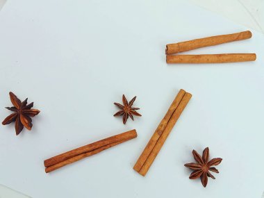 Tarçın çubuklarından ve beyaz arka planda yıldız anasonundan oluşan minimum düz bir bileşim. Yemek pişirme, tarif tasarımı ve ambalaj için kopyalama alanı olan basit yiyecek arkaplanı.