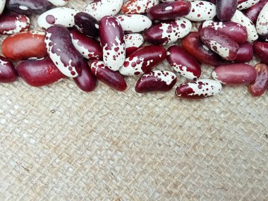 Makro, doğal kumaş arka planında kırmızı ve beyaz benekli fasulyeleri kapat..