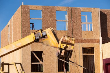 Yeni ev ahşap çerçevesinin yanındaki sarı vinç.