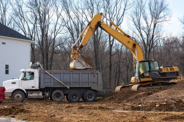 Kazıcı, bahşiş kamyonu kirliliğine toprak döküyor.