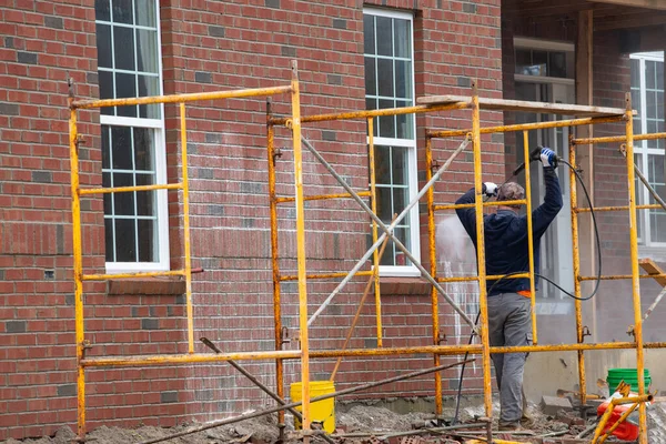 Washing the walls of a brick house water job nozzle walls — Stock Image Washing Walls Brick House Water Job Nozzle Walls Royalty Free Stock Photos
