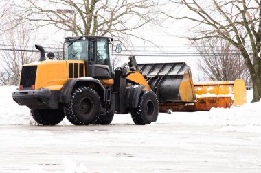 Sarı traktör karı kaldırır.