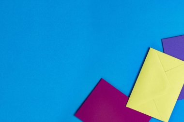 Mavi arkaplanda üç renkli zarf var.