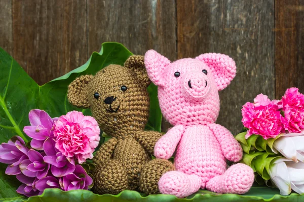 Bära docka och gris docka med blommor på trä bakgrund — Stockfoto