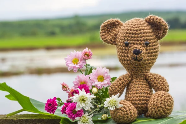 单一的熊娃娃和自然背景上的花朵 — 图库照片