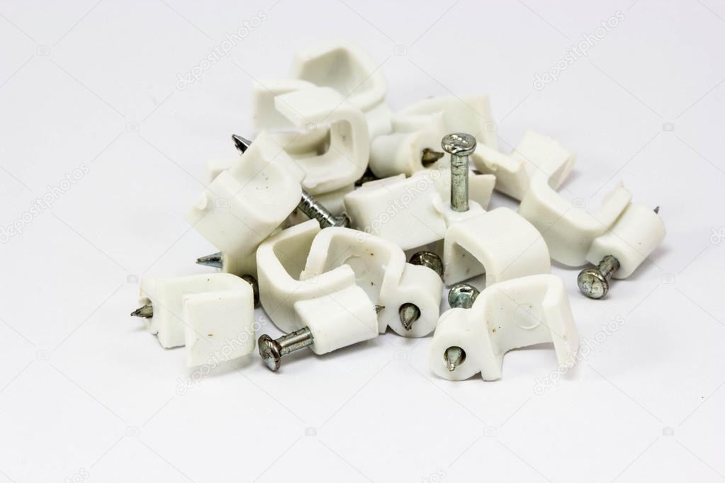 White plastic cable clips with nails on white background