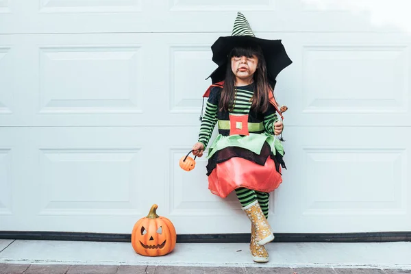 Boszorkánynak Öltözött Lány Cukorkát Eszik Halloweent Ünnepli Garázsajtóban Jack Lantern — Stock Fotó