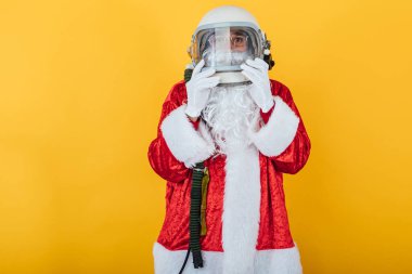 Sarı arka planda astronot kaskı olan Noel Baba. Noel konsepti
