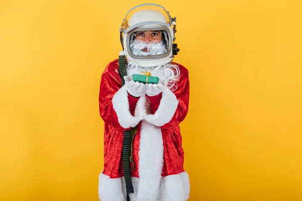 Der Weihnachtsmann Mit Astronautenhelm Hält Ein Geschenk Auf Gelbem Hintergrund — Stockfoto