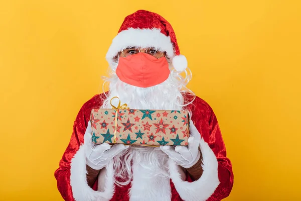 Papai Noel Vestindo Uma Máscara Vermelha Segurando Presente Fundo Amarelo — Fotografia de Stock