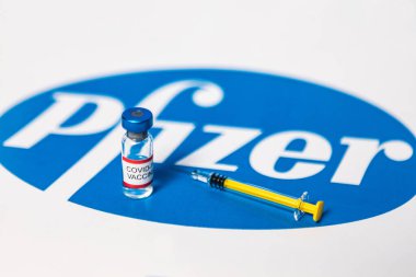MADRID, SPAIN - 25, 2021: Pfizer logosu üzerinde Covid-19 aşısı ve şırınga bulunan şişe