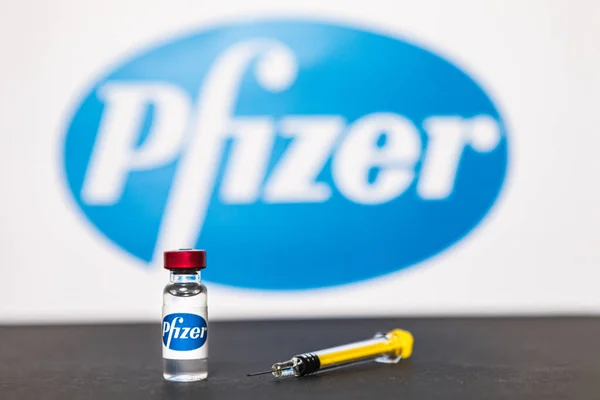 MADRID, SPAIN - 25, 2021: Arka planda Pfizer şirketinin logosunun bulunduğu covid-19 aşısı ve şırınga dolu şişe