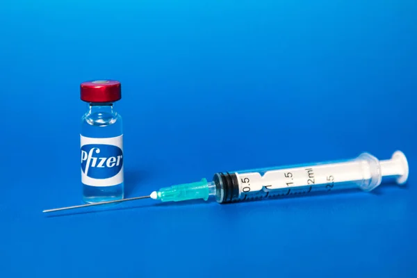 MADRID, SPAIN - JAN, 25, 2021: Mavi arka planda Covid-19 aşısı ve şırıngayla dolu Pfizer şirket logosu