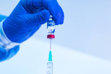 MADRID, SPAIN - JAN, 25, 2021: Doktor şırınganın şırıngasını COVID-19 aşı şirketi Pfizer 'ın aşılamak için şişeye sokuyor. Coronavirus aşısı konsepti