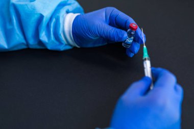 MADRID, SPAIN - 25, 2021: COVID-19 Pfizer şirketi aşısı bir doktorun elinde ve diğer taraftan bir şırınga. Coronavirus aşısı konsepti