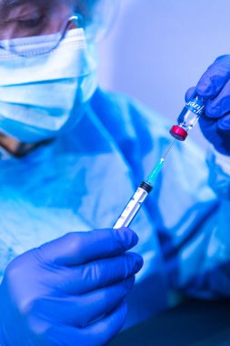 MADRID, SPAIN - JAN, 25, 2021: Doktor şırınganın şırıngasını COVID-19 aşı şirketi Pfizer 'ın aşılamak için şişeye sokuyor. Coronavirus aşısı konsepti