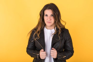 Sarı arka planda siyah deri ceket giyen genç bir kız..
