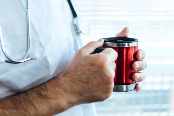 Mature male doctor - nurse having coffee in a hospital window. Covid-19 and medicine concept