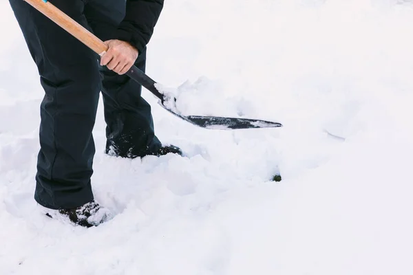 Man removing snow from the garden of his house with a shovel