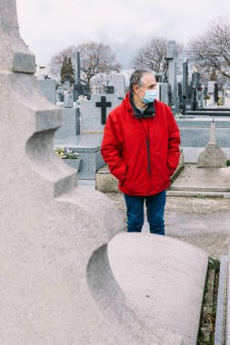 Maske takan, üzgün ve dua eden bir adam, 19. yüzyılda ölmüş bir akrabasının mezarının önünde.