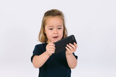 Küçük sarışın kız cep telefonuna bakıyor.