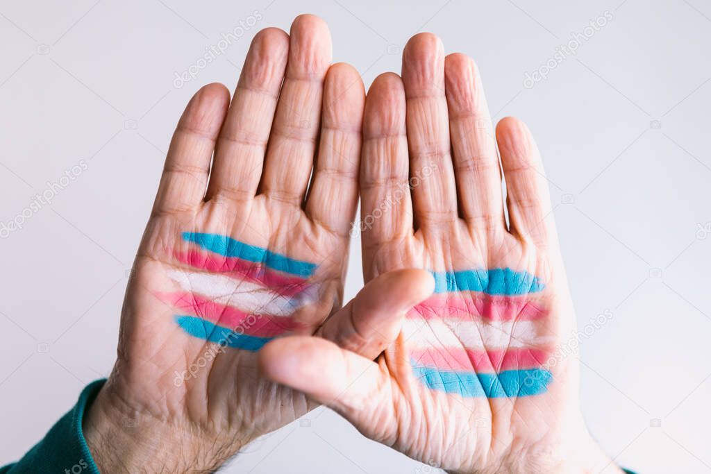 Transsexual man raises his hands with the transsexual flag painted on the palms