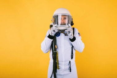 Uzay giysisi ve kasklı erkek kozmonot, sarı arka planda sisli camlı miğfer..