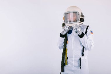 Uzay giysisi ve kasklı bir erkek kozmonot. Beyaz arka planda kaskı elleriyle tutarken şaşırmış..