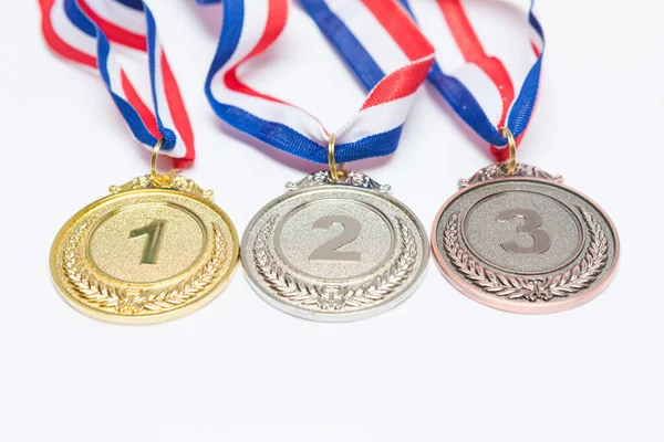 Beyaz arka planda birinci, ikinci ve üçüncü olmak üzere altın, gümüş ve bronz spor madalyaları. Olimpiyat oyunları ve spor konsepti.