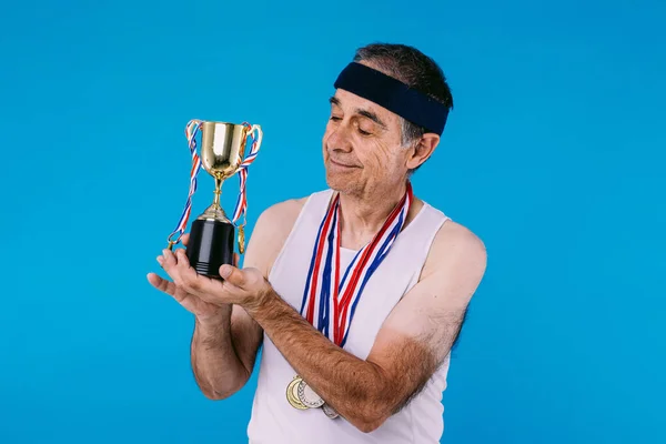 Starszy Sportowiec Śladami Słońca Ramionach Trzema Medalami Szyi Patrzącymi Trofeum — Zdjęcie stockowe