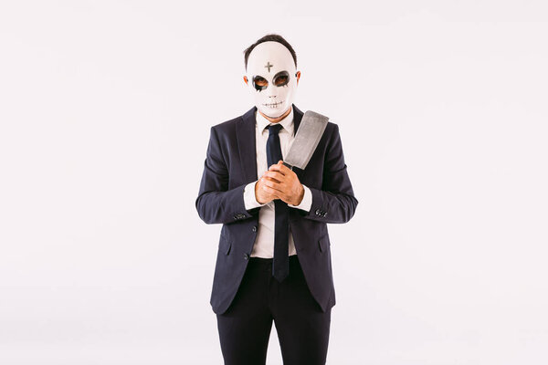 Мужчина в костюме и галстуке, в маске убийцы с крестом на лбу на Хэллоуин, угрожал ножом. Карнавал и празднование Хэллоуина