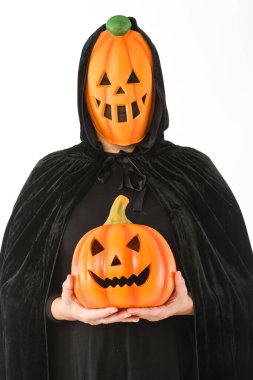 Balkabağı Jack-O-Lantern maskesi ve kapüşonlu kadife pelerin giymiş beyaz arka planda elinde balkabağı tutan biri. Karnaval, Cadılar Bayramı ve ölü konseptin günü.
