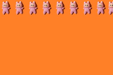 Pembe Labubu oyuncaklarının deseni, üstünde, turuncu bir arka planda. Cadılar Bayramı, bebek, koleksiyon, şeytani, Çince, çocukluk ve korku.