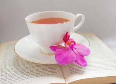 Orchid and a cup of tea on a book