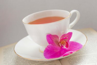 Orchid and a cup of tea on a book
