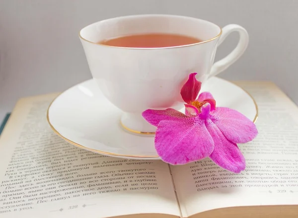 Orchid and a cup of tea on a book — Stock Photo, Image