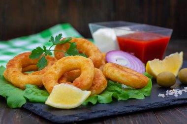 Kızarmış kalamar ya da balık halkaları aperatifi. Limon, ketçap ve mayonez ile haşlanmış mürekkep balığı veya balık halkaları. Kara tahtada altın, çıtır çıtır kalamar atıştırmalığı.