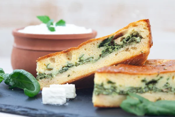 Spinach and cheese quiche tart served with yoghurt in clay bowl.  Spinach pie for healthy breakfast.